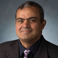 Man in a brown suit, with a grey background.