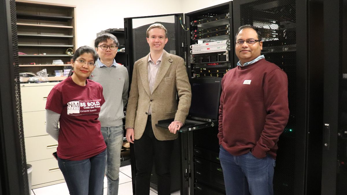 Four people in a computer system room.